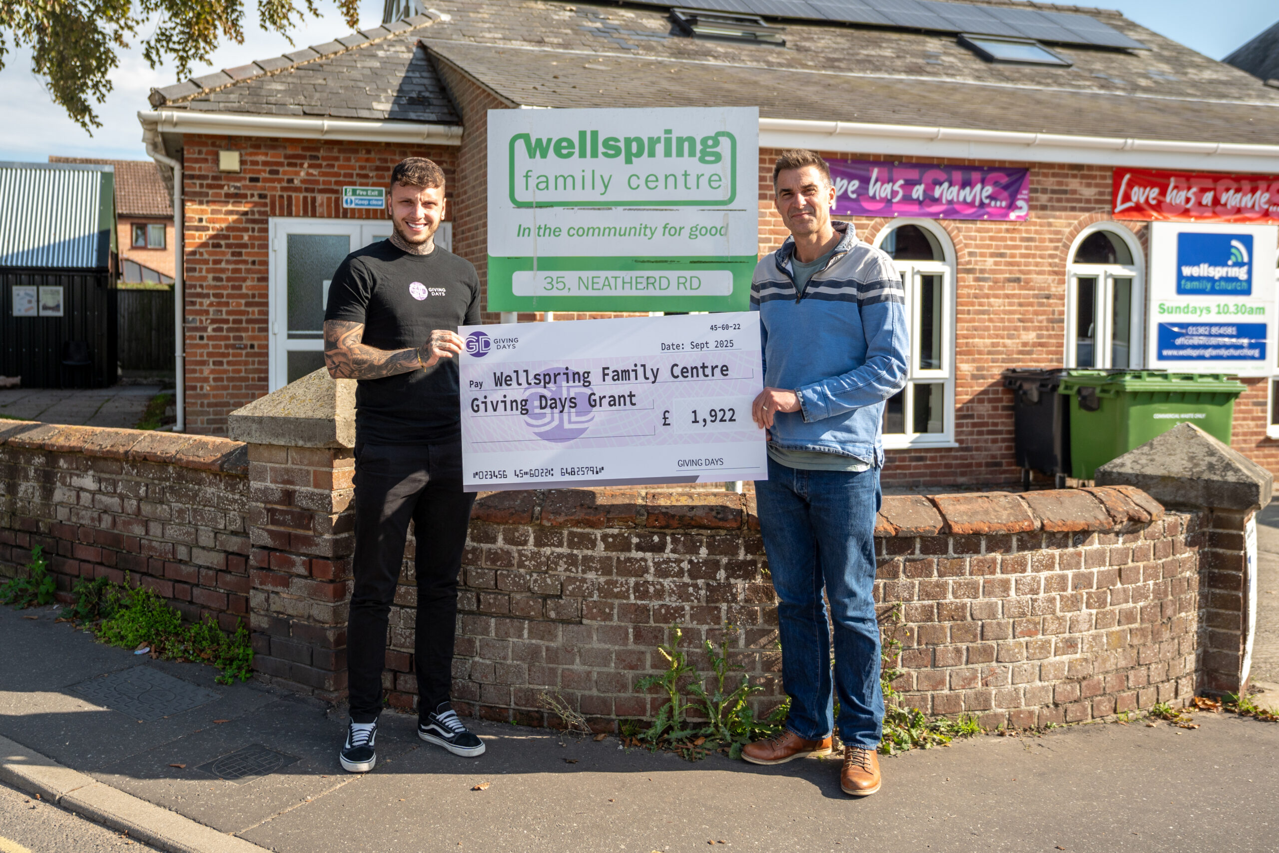 Two people standing and holding a large cheque
