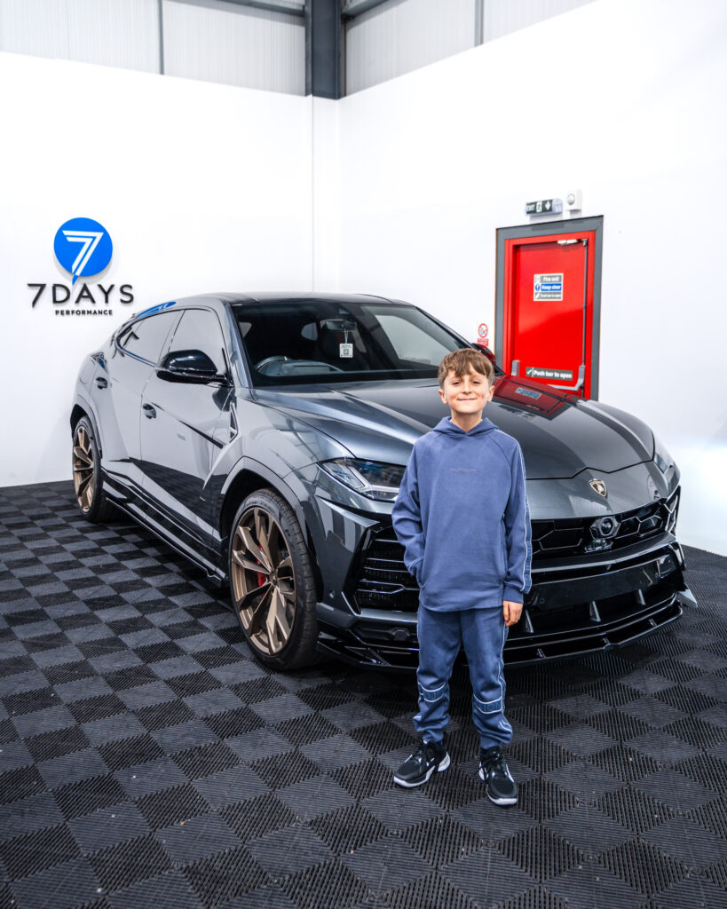 A child standing in front of a supercar
