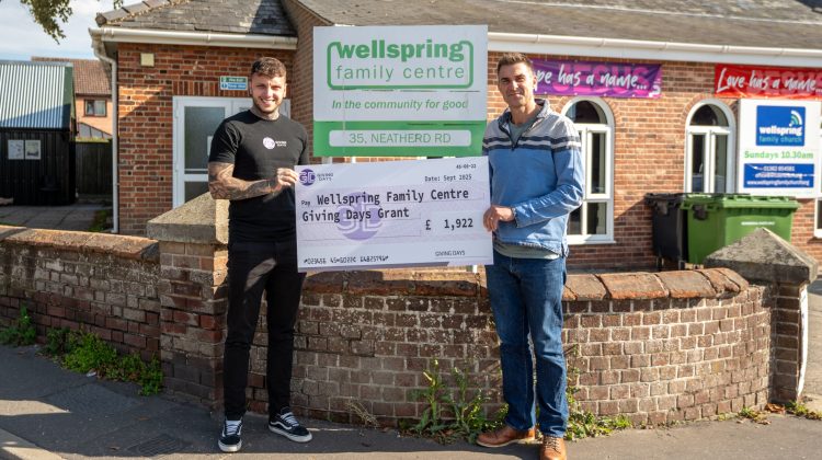 Two people standing and holding a large cheque